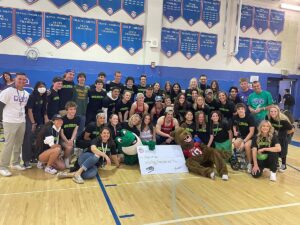 A group photo in the gymnasium of all of the Cherry Creek High School kids with Chuckles, the mascot, and the large donation check.