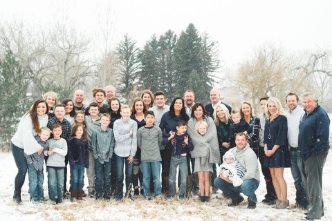 a photo of the entire Rudden family. They are outside in the winter time with pine trees behind them and falling snow.