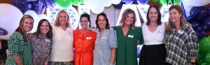Group staff photo with 8 women with arms around each other and bags of fun balloons behind them.